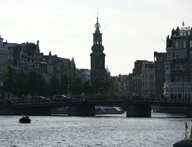 a bridge over a body of water with a clock tower in the background